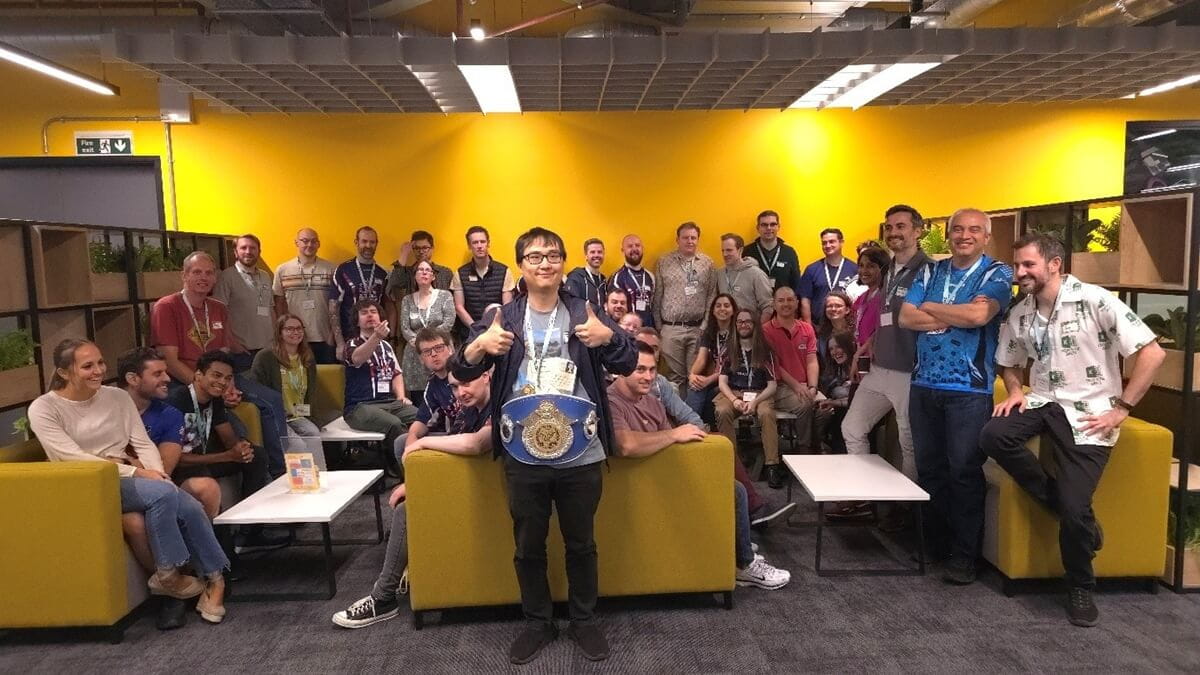 a group photo of lots of people with one individual at the front wearing a WWE style champio's belt