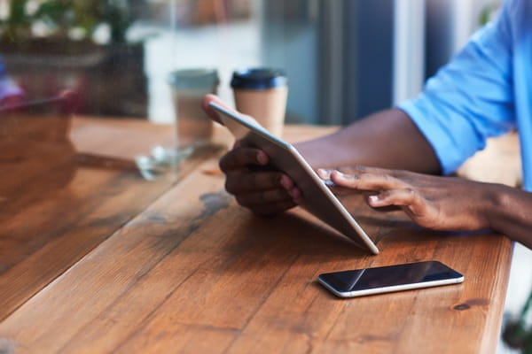 Person sat at a table using a tablet computer.