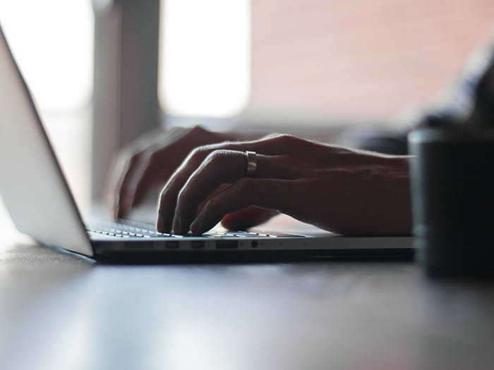 Hands typing at a laptop