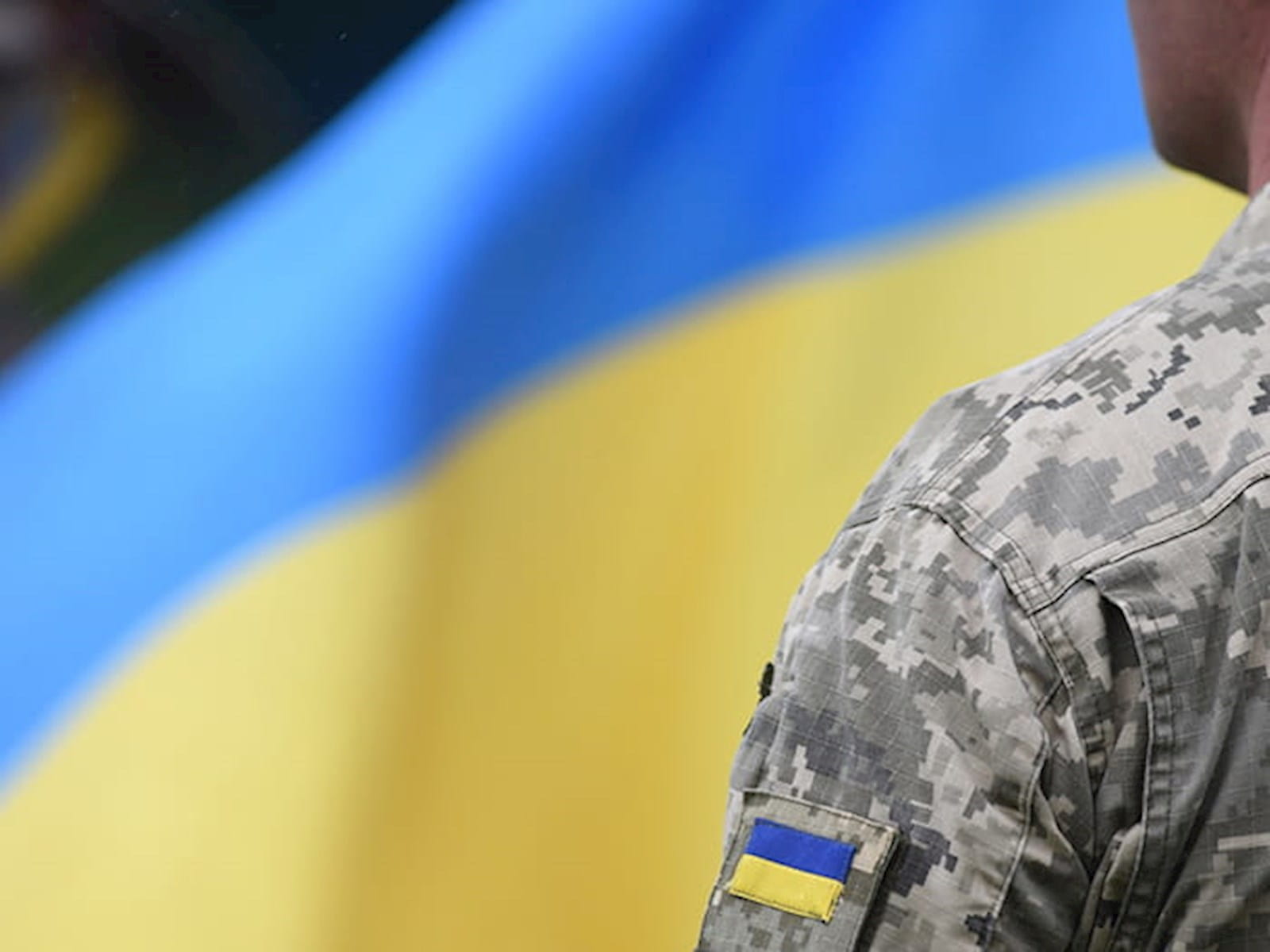 Soldier in front of Ukrainian flag