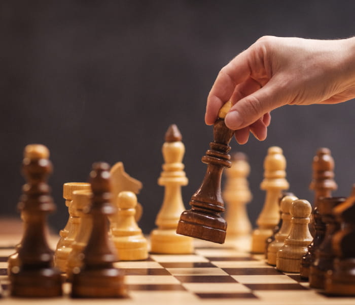 A hand picks up a chess piece from the chessboard, ready to make the next move