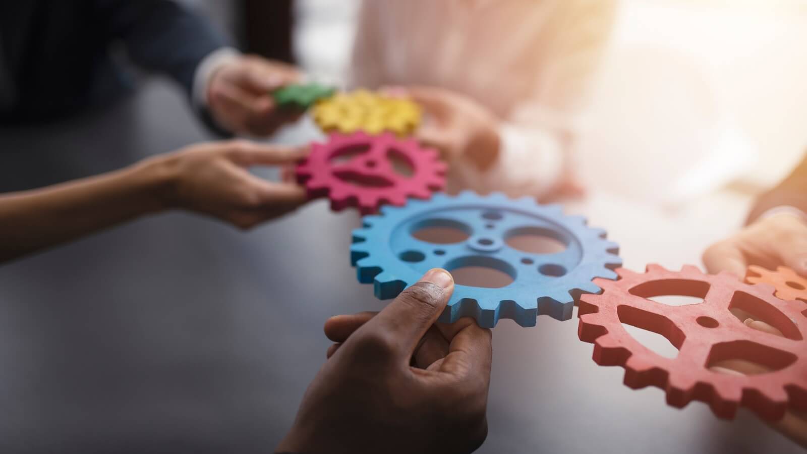Business team holding a line of interlinked cogs
