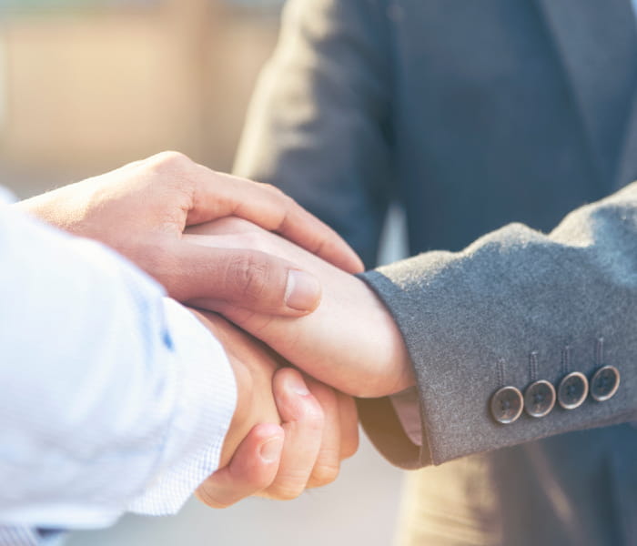 Two businessmen clasping their hands in greeting and support.