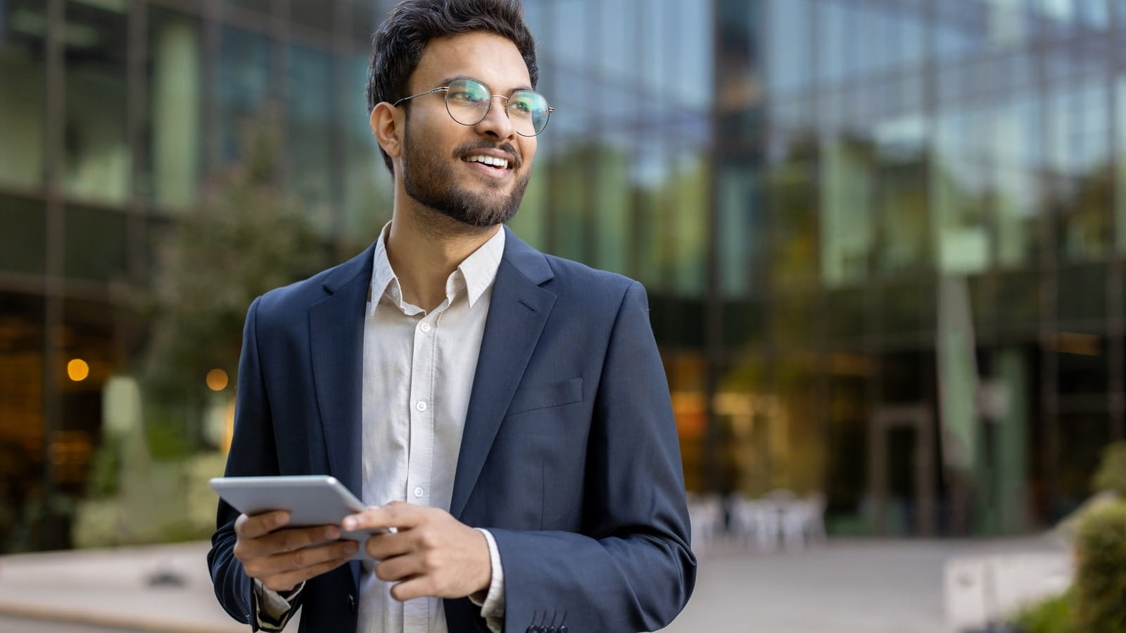 Young businessman outside an office building, holding a tablet.