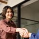 Young female office worker shaking hands with a colleague across the desk.