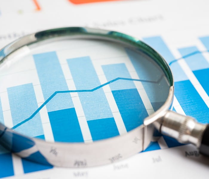 A magnifying glass resting on a report. The reports shows generic charts.