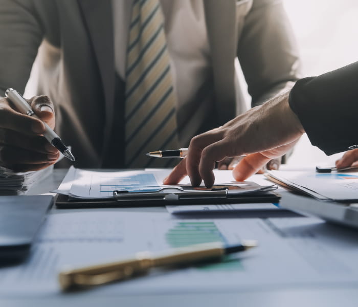 Two people sit at their desks, surrounded by scattered paperwork